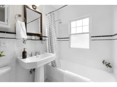 Cottage bathroom with white tile, pedestal sink and patterned shower curtain