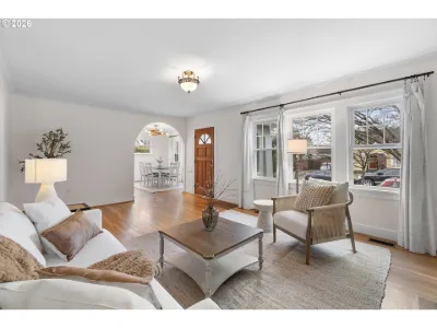 Cottage living room staged with a cream sofa and armchair, looking toward an arched hallway