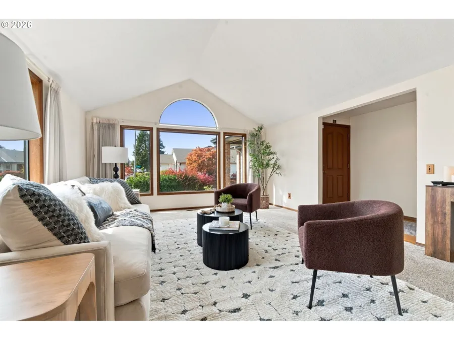 Vacant home fully staged with a cream sofa, two plum accent chairs and a patterned rug under an arched window