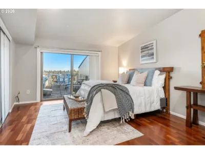 Staged bedroom with white bedding, a knit throw and glass doors to a balcony