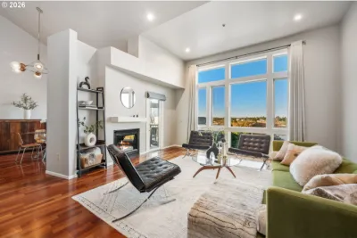 Staged penthouse condo living room with a leather lounge chair, green sofa and tall windows
